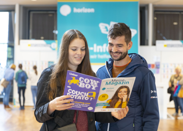 Eine Schülerin und ein Schüler lesen zusammen das Messemagazin in der Messehalle der Horizon Karlsruhe 2022