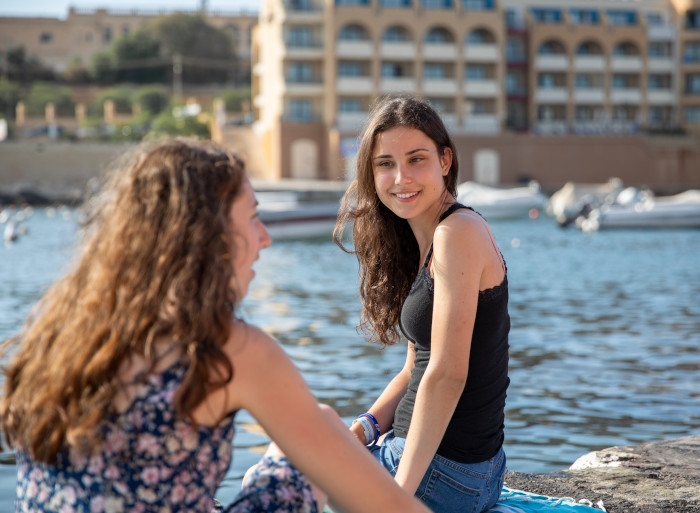 Zwei Frauen sitzen auf Malta am Meer.