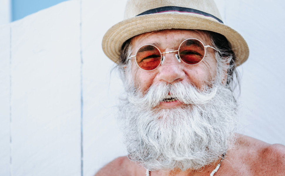 Älterer lachender Mann mit Sonnenbrille, Bart und Hut